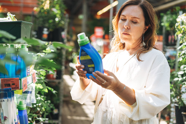 Particulier en train de vérifier la mention des pesticides autorisés en magasin botanique
